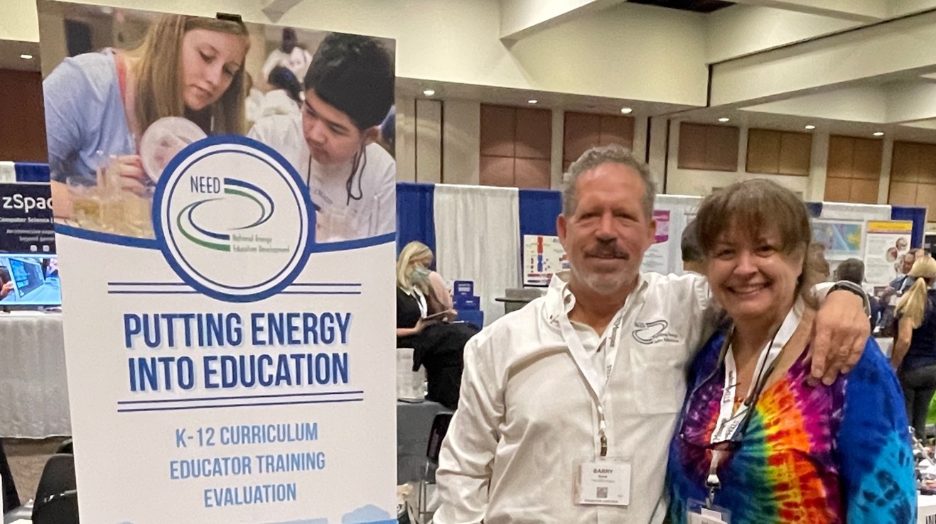 Teacher standing next to a "putting energy into education" sign