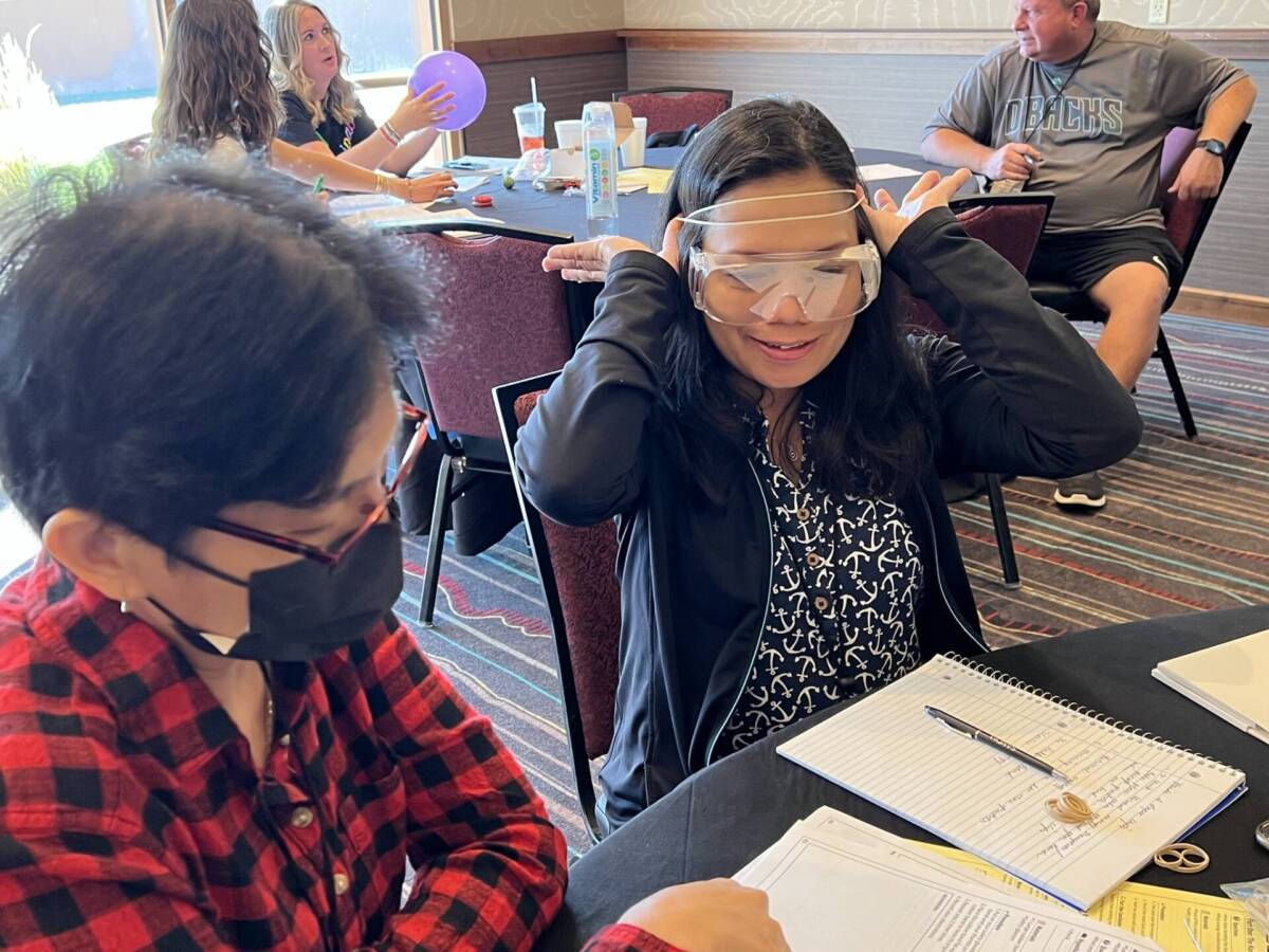 Teachers wearing safety goggles doing experiments at a conference