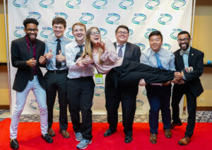 Students in front of a step and repeat banner horsing around