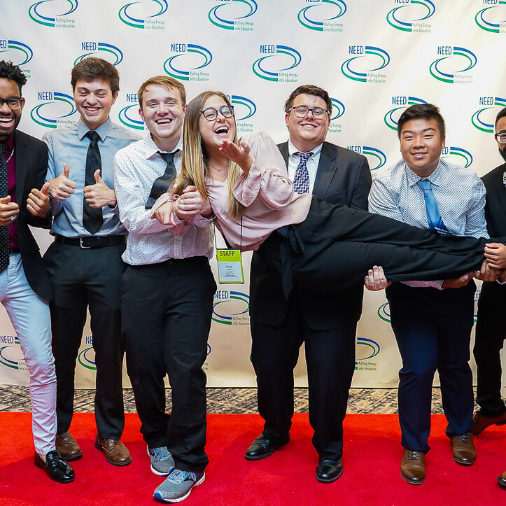 Students in front of a step and repeat banner horsing around