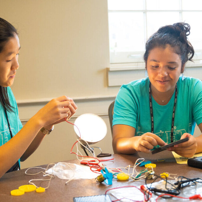 Two high school girls working at an electrical science experiment